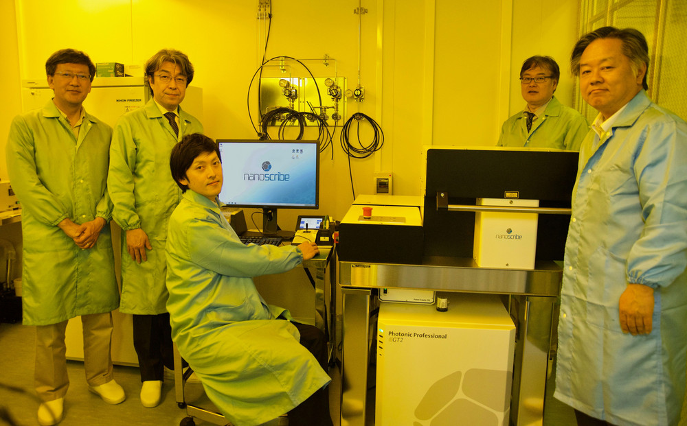 Several men from KEIO University standing around Nanoscribe's Photonic Professional GT2 in a lab.